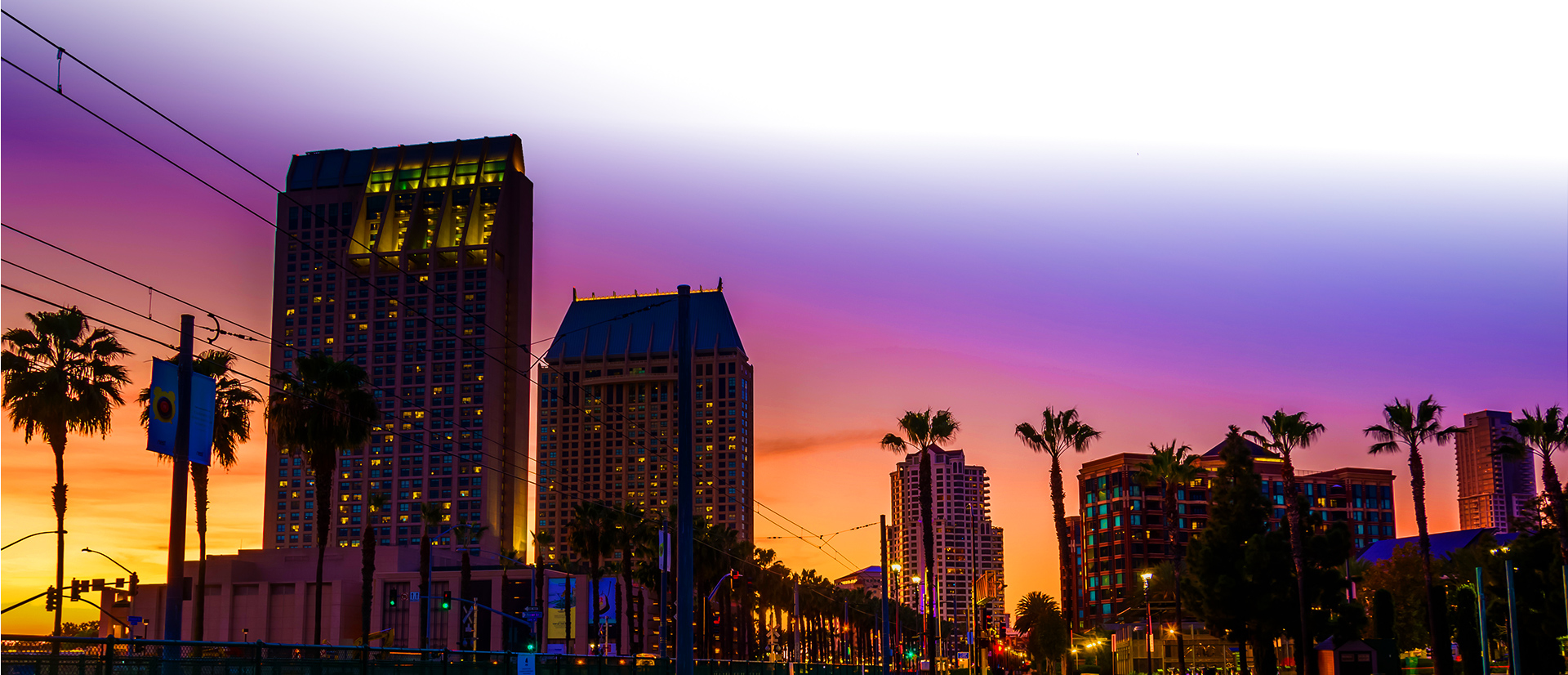 City buildings silhouette against an orange-purple gradient sky
