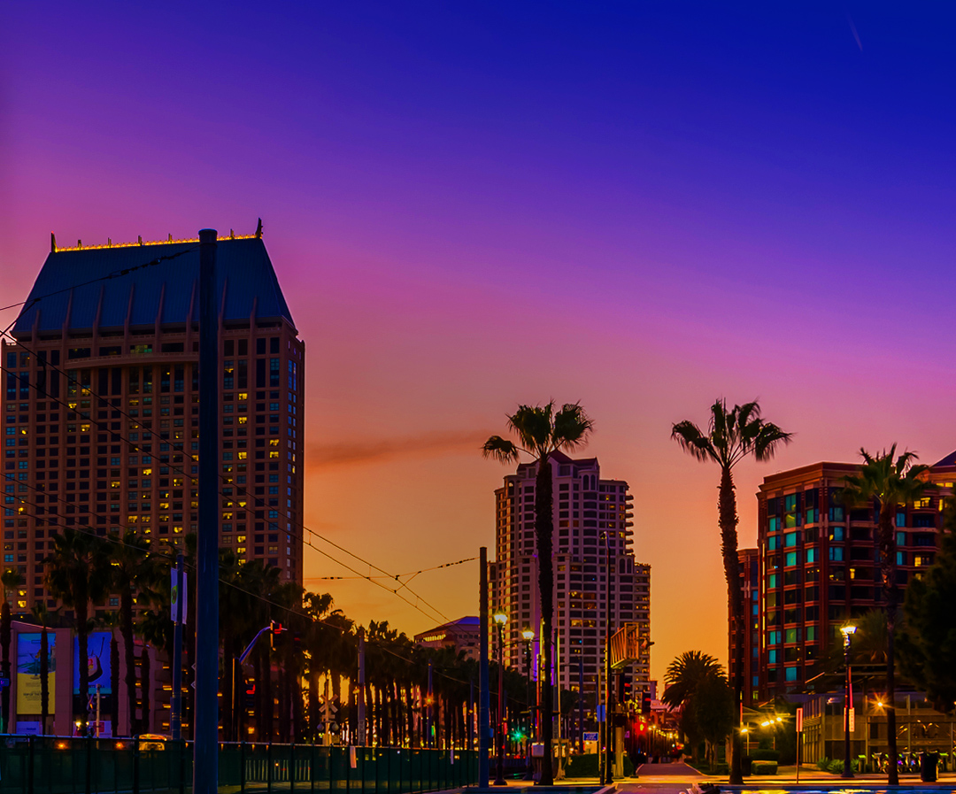 City buildings silhouette against an orange-purple gradient sky